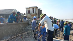 Người dân và lực lượng chức năn gia cố kè biển Cẩm Nhượng bị sạt lở