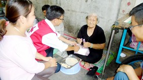 Các hội viên Hội Chữ thập đỏ phường 6, quận 4 tặng cơm các cụ già nghèo khó, neo đơn