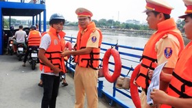 Cảnh sát giao thông đường thủy TPHCM hướng dẫn khách đi phà mặc áo phao để đảm bảo an toàn
