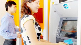 Khách hàng sử dụng thẻ ATM ngân hàng        Ảnh: THÀNH TRÍ