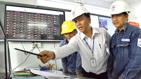Kỹ sư Đỗ Tiến Trung (giữa) và đồng nghiệp giám sát hệ thống lưới điện  tại Trung tâm quản lý lưới điện Hóc Môn
