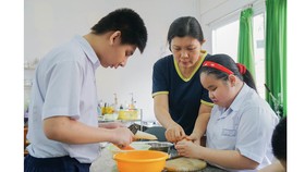 Cô Nguyễn Thị Kim Phượng hướng dẫn học trò những kỹ năng  hàng ngày, giúp các em hòa nhập với cuộc sống. Ảnh: HOÀNG HÙNG 