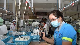 Công nhân đang làm việc tại một một nhà máy bảo đảm công tác phòng chống dịch tại Long An, đầu tháng 7-2021. Ảnh: VGP