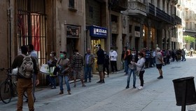 Người dân xếp hàng khi các tình nguyện viên phân phát thực phẩm tại nhà thờ Santa Anna ở Barcelona vào ngày 15/5/2020. (Nguồn: AFP)