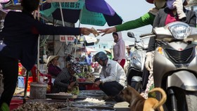 A vendor hands money to a motorist as people buy seafood at the Duong Dong market in Phu Quoc, Vietnam. Photographer: Maika Elan/Bloomberg , Bloomberg