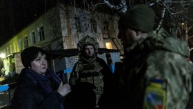 Các thành viên lực lượng vũ trang Ukraine nói chuyện với một người dân địa phương bên ngoài một trường mẫu giáo bị thiệt hại do pháo kích, ở Stanytsia Luhanska, thuộc vùng Luhansk, Ukraine. (Ảnh: Reuters)