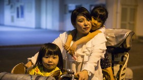 Masami Onishi, 23 tuổi, cùng với các con gái của mình, Yua, 3 tuổi và Sora, 6 tuổi, trên một chiếc xe đạp. Ảnh chụp khi họ đến Nishinari Kids' Dining Hall, nơi có thể vui chơi và nhận được đồ ăn miễn phí của nhóm cộng đồng