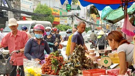 Khách hàng chọn mua bánh ú, trái cây sát chợ Hòa Hưng, quận 10, TPHCM, sáng 18-6. Ảnh: THI HỒNG