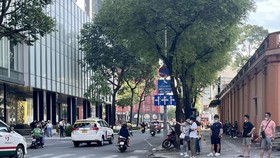 Các bạn trẻ và khách du lịch đón taxi phía ngoài cổng trung tâm thương mại ở TPHCM. Ảnh: HOÀNG HÙNG