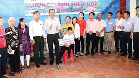 Ông Lưu Hoàng Tân - Chủ tịch, Giám đốc Công ty TNHH MTV Xổ số kiến thiết Đồng Tháp (thứ năm từ trái sang) trao học bổng cho em Nguyễn Thị Anh Đào