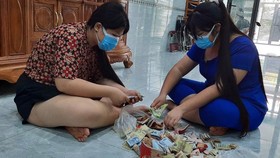 Hai chị em Phan Ngọc Phương Trinh và Phan Ngọc Phương Vy đập heo đất để lấy tiền ủng hộ quỹ