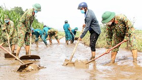 Các chiến sĩ bộ đội cùng lực lượng dân quân xung kích huyện Sơn Hòa (tỉnh Phú Yên) khắc phục bùn lũ, nhà cửa thiệt hại giúp người dân sớm ổn định cuộc sống. Ảnh: MINH CHÂU