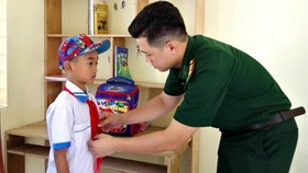 Cán bộ Đồn biên phòng Phú Gia chuẩn bị đồng phục cho em Lê Văn Hoàng đến trường