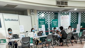 Một phụ nữ Singapore được tư vấn về những tác dụng phụ sau khi chích mũi vaccine thứ 3 trước khi lấy giấy chứng nhận, tại một trung tâm tiêm chủng cộng đồng do Tập đoàn Y tế Raffles Medical điều hành theo ủy nhiệm của chính phủ. 