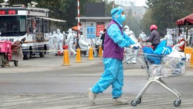 Nhân viên phòng chống và kiểm soát dịch bệnh cung cấp nhu yếu phẩm hàng ngày cho một khu phố Bắc Kinh đang bị phong tỏa.