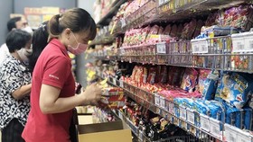 Nhân viên nhãn hàng bổ sung thêm hàng hóa thiết yếu lên kệ tại siêu thị ở TP Hồ Chí Minh. (Ảnh: Mỹ Phương - TTXVN.)