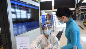 Hành khách kê khai bản cam kết phòng, chống dịch COIVD-19 tại sân bay Nội Bài - Ảnh: HOÀNG ANH