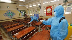 Nhân viên Trường tiểu học Lương Định Của, quận 3, TP.HCM vệ sinh khử khuẩn phòng học chuẩn bị đón học sinh lớp 1 đi học trở lại - Ảnh: NHƯ HÙNG