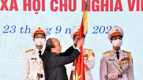 Chủ tịch Nước Nguyễn Xuân Phúc gắn Huân chương Lao động hạng Nhất lên lá cờ truyền thống của Ủy ban Quốc phòng và An ninh của Quốc hội. Ảnh: VIẾT CHUNG