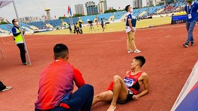 Nguyễn Tiến Trọng nhanh chóng giúp người đồng đội Trần Văn Đảng cởi giầy, sơ cứu ngay khi bị đau sau khi kết thúc thi đấu 800m. Ảnh: MINH CHIẾN