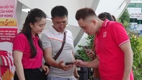Các nhân viên đang hướng dẫn người dân thực hiện thanh toán không tiền mặt