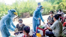Nhân viên Trung tâm Y tế huyện Bình Chánh lấy mẫu xét nghiệm người dân tại tại chợ Tân Đoàn Việt - Phong Phú vào sáng 2-5. Ảnh: MINH NAM
