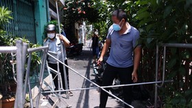 Lực lượng tháo gỡ các thanh rào chắn bằng sắt ở phường 9, quận Phú Nhuận. Ảnh: DŨNG PHƯƠNG