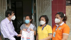Ông Phạm Trường, Phó Tổng Biên tập Báo SGGP (bìa trái), thay mặt ban tổ chức chương trình Đồng hành vượt cạn trao hỗ trợ cho thai phụ ở quận 3, TPHCM. Ảnh: DŨNG PHƯƠNG