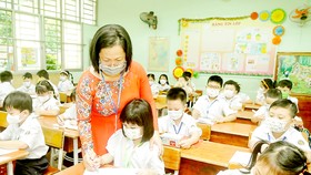 Học sinh lớp một Trường Tiểu học Nguyễn Đình Chiểu, quận Bình Thạnh, TPHCM được cô giáo hướng dẫn viết chữ trong ngày đầu học trực tiếp. Ảnh: CAO THĂNG