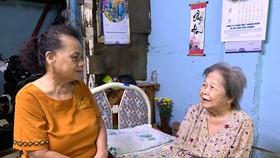 Bà Nguyễn Thị Hường, Phó Chủ nhiệm CLB Hội mẹ truyền thống quận 1 (trái), thăm hỏi sức khỏe một hộ nghèo tại phường Đa Kao. Ảnh: THÁI PHƯƠNG