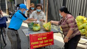 Người dân tại điểm phong tỏa phường 12, quận Tân Bình nhận hàng từ các địa phương hỗ trợ