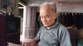 Ông Vương Khả Khai bên tập giấy tờ ghi chép  tìm kiếm phần mộ liệt sĩ