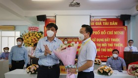 Ông Lê Hòa Bình, phó chủ tịch UBND TP, trao hoa chúc mừng đơn vị trúng đấu giá lô đất 3-5 - Ảnh: NHẬT THỊNH
