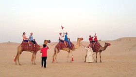 Vietnamese tourists take an opportunity to go ride on a camel in the desert in Dubai.