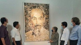 Painter Le Thi Kim Bach (3rd, R) introduces her stone painting on Uncle Ho to viewers at the exhibition.