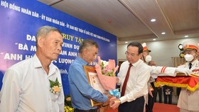 Secretary of the HCMC Party Committee Nguyen Van Nen (R) presents the "Vietnamese Heroic Mother" title to relatives of mothers.