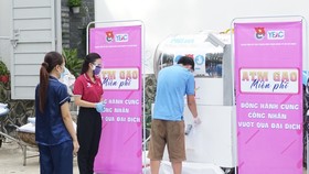 Thành niên công nhân tại khu lưu trú nhận gạo từ "máy ATM"