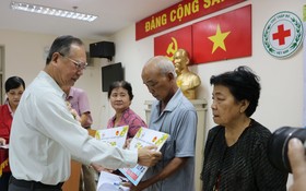穗城會館理事長盧耀南向貧困同胞贈送醫保卡。