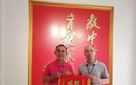 黃智球老師（左）代表本市華文老師團向組委會陳進超校長贈送紀念錦旗。