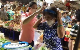 第十四坊婦女會主席向華人商販戴上防護面罩。