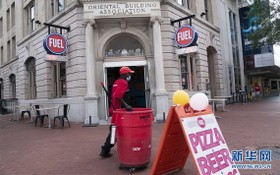  7月17日，在美國首都華盛頓，一名清潔工經過一家重新開業的餐館。（圖源：新華社）