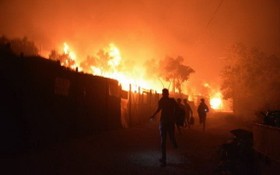 當地時間9月9日，希臘萊斯博斯島的莫里亞難民營發生大火後，難民離開著火地。（圖源：AP）