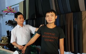 范勇（左）為顧客量身定制衣服。