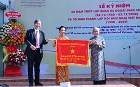市各友好組織聯合會王德煌軍（左）向市越南-古巴友好協會代表贈送市人委會傳統錦旗。（圖源：明協）