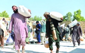 人們在阿富汗坎大哈領取由世界糧食計劃署提供的物資援助。（圖源：新華社）