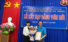 越南-新加坡工業區工會黨支部書記鄧氏金芝向新黨員頒授接納入黨《決定》。