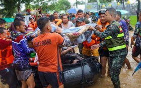 救援人員協助居民從洪災區轉移。（圖：新華社）