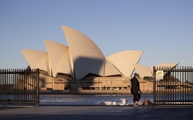 一名婦女在澳大利亞悉尼的悉尼歌劇院附近遛狗。（圖：新華社）
