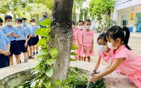 守德市黎文越小學的學生使用洗手水給樹木澆灌。