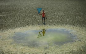 一名小男孩站在孟加拉國干旱地區的一個水坑前。（圖：聯合國）